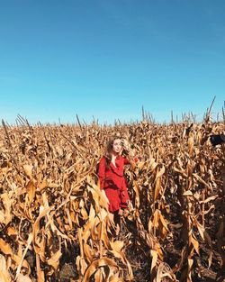 Woman walking in field against clear blue sky