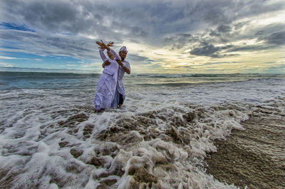 Full length of woman at beach against sky during sunset