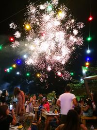 Group of people watching firework display at night