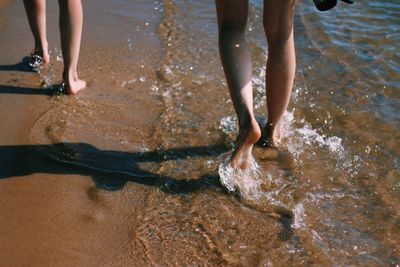 Low section of women walking on shore