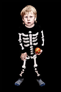 Portrait of boy standing against black background