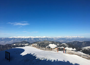 Snow covered landscape against blue sky