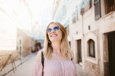 Happy blonde woman with sunglasses and hat enjoying tourism in majorca