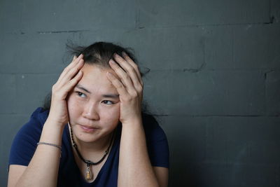 Close-up of thoughtful woman against wall