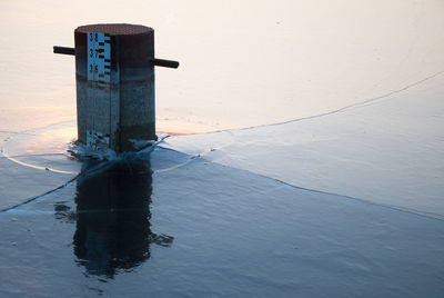 Information sign by sea against sky during sunset