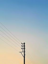 Low angle view of silhouette electricity pylon against sky during sunset