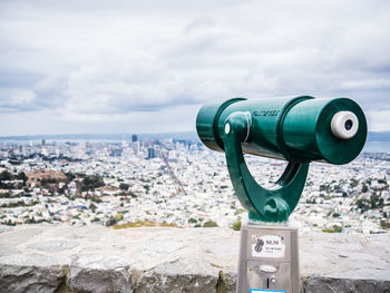 Close-up of coin-operated binoculars against cityscape