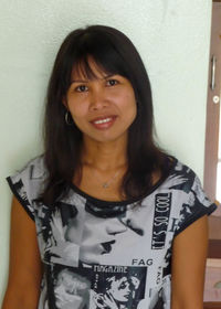 Portrait of smiling young woman standing against wall