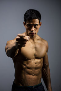 Shirtless muscular man standing against gray background