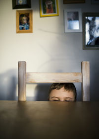 Boy hiding behind table at home