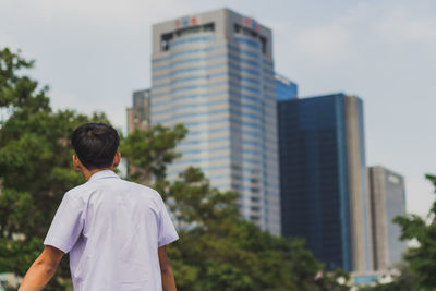 Rear view of man standing against buildings in city