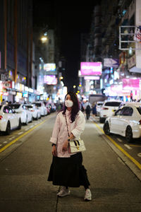Woman standing on city street at night
