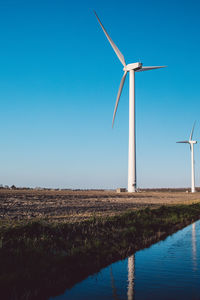 Windmill on field against clear blue sky