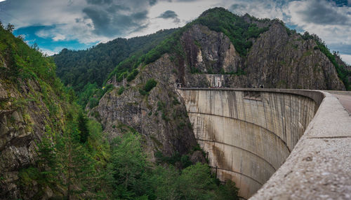 View of dam on mountain against cloudy sky