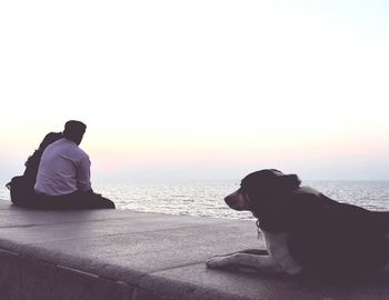 People relaxing on beach at sunset