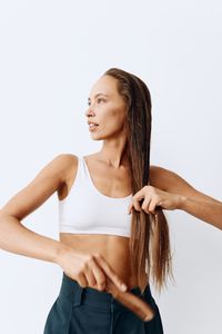 Portrait of young woman standing against white background