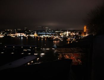 High angle view of illuminated buildings by river against sky at night