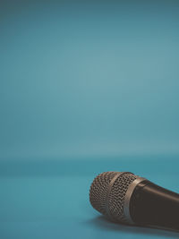 Close up of dynamic microphone with mid blue background and copy space