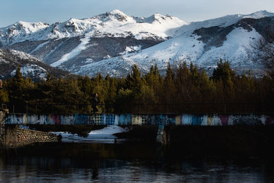 Scenic view of lake by snowcapped mountains against sky