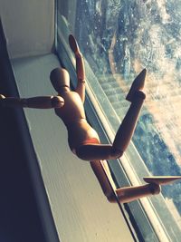 Low angle view of figurine in mid-air by window at home