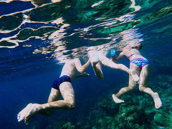 Low section of people swimming in sea