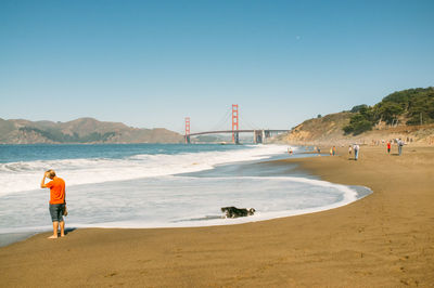 Man standing at beach against clear sky