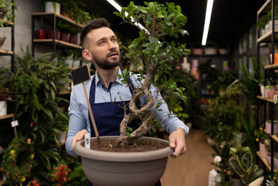 Portrait of smiling woman holding potted plant