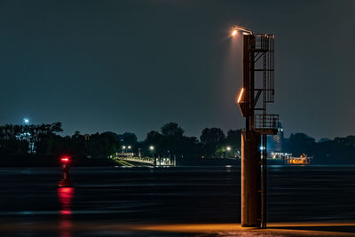 Illuminated street lights against sky at night