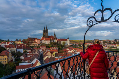 Rear view of woman standing by railing against buildings