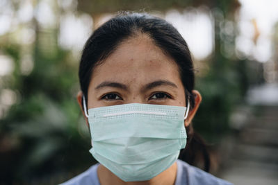 Close-up of woman looking away while wearing mask against trees