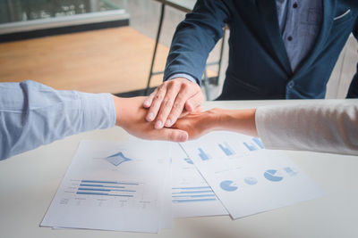 Colleagues stacking hands over table in office