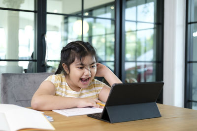 Portrait of girl sitting on table at home