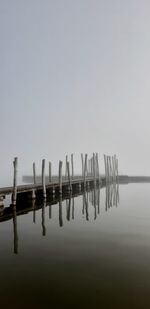 Wooden posts in lake against clear sky