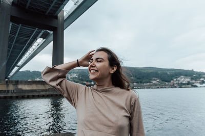 Portrait of young woman standing against lake