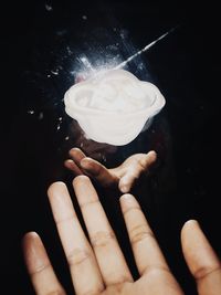 Close-up of person holding ice cream cone against black background
