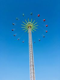 Low angle view of chain swing ride against clear blue sky