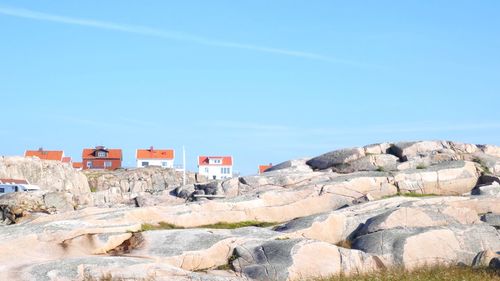 Rocks by sea against clear blue sky
