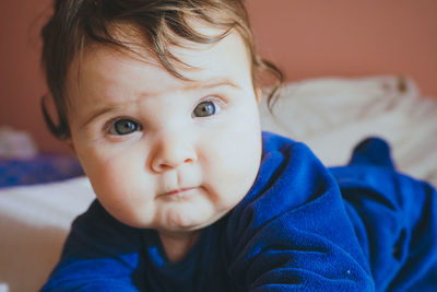 Portrait of cute baby girl on bed at home