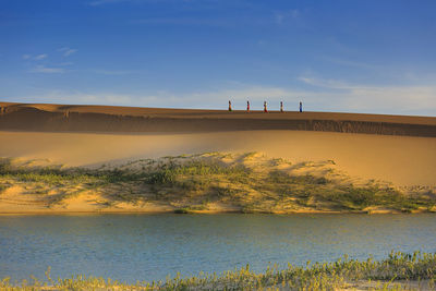 View of women carrying water on sand dune