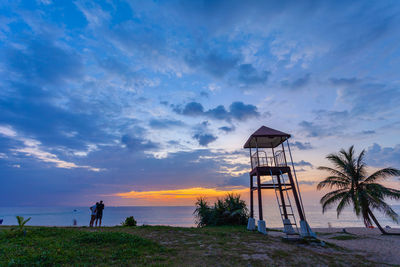 Lifeguard hut on beach against sky during sunset