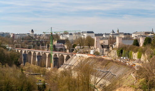 Bridge over river amidst buildings in city against sky