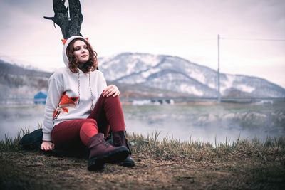 Young woman sitting on lake against mountains