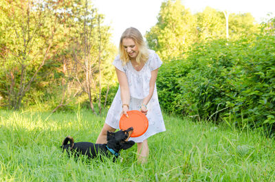 Happy woman holding umbrella while standing on field