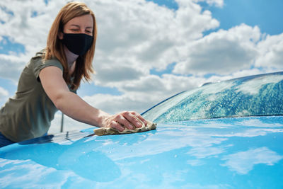 Hand cleaning modern blue car with microfiber cloth