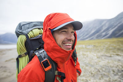 Portrait of happy backpacker with red rain jacket on.