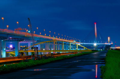 Illuminated bridge over river against sky at night