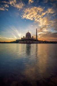 Putra mosque by lake against sky during sunset in city