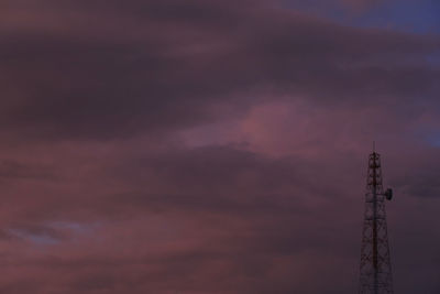 Low angle view of communications tower against cloudy sky