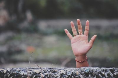 Cropped hand waving behind retaining wall