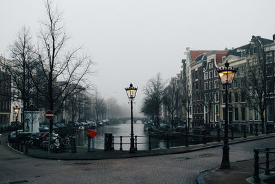 Canal amidst buildings against sky during winter